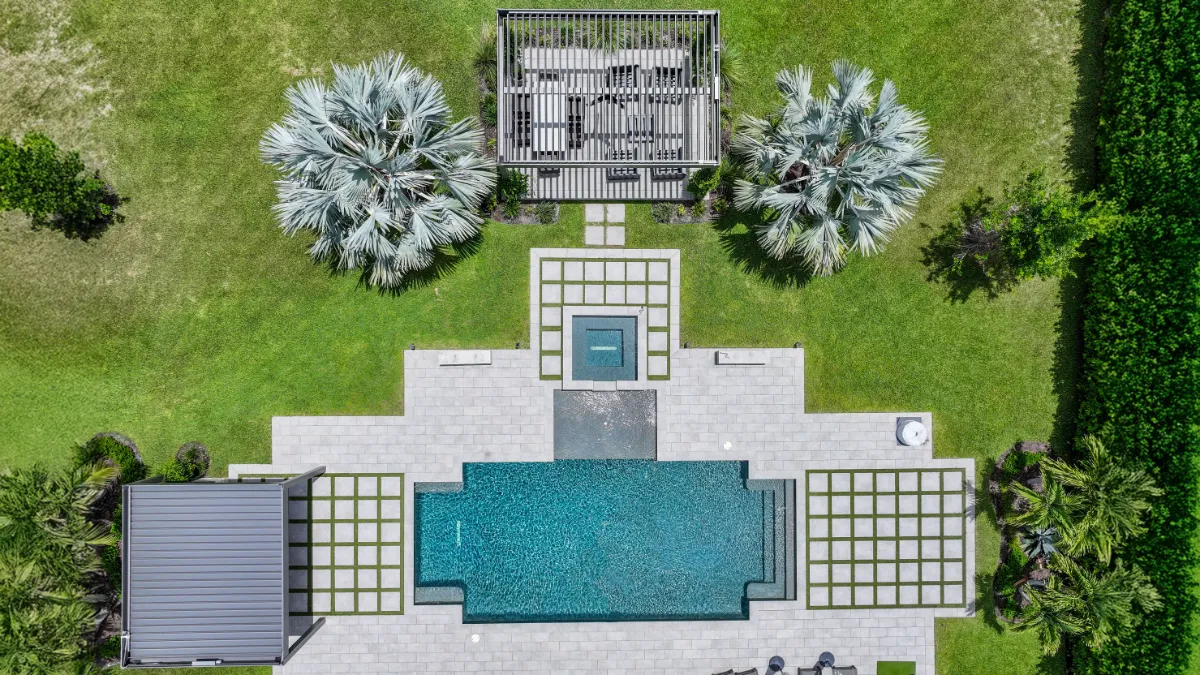 Aerial view of a landscaped backyard with dual smart pergolas, pool, spa, and symmetrical modern paver design.