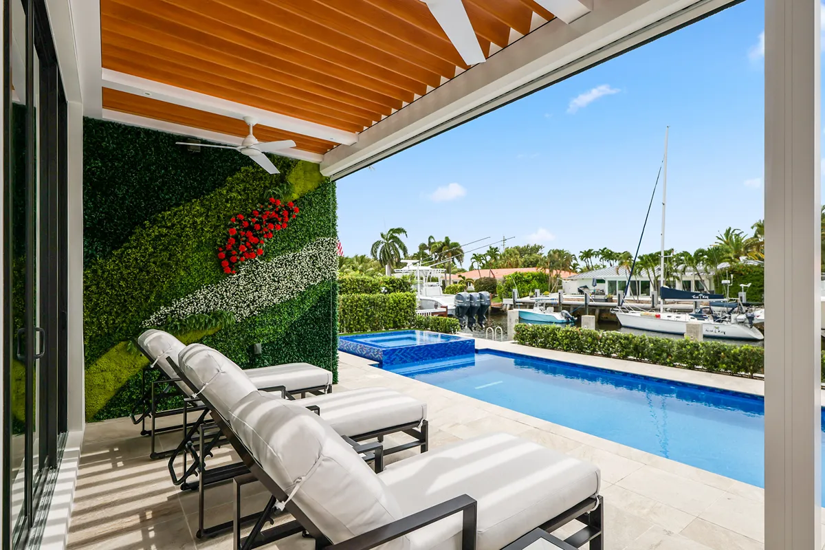 Stylish outdoor lounge beneath a modern pergola with a sleek, louvered roof system, blending comfort with high design.