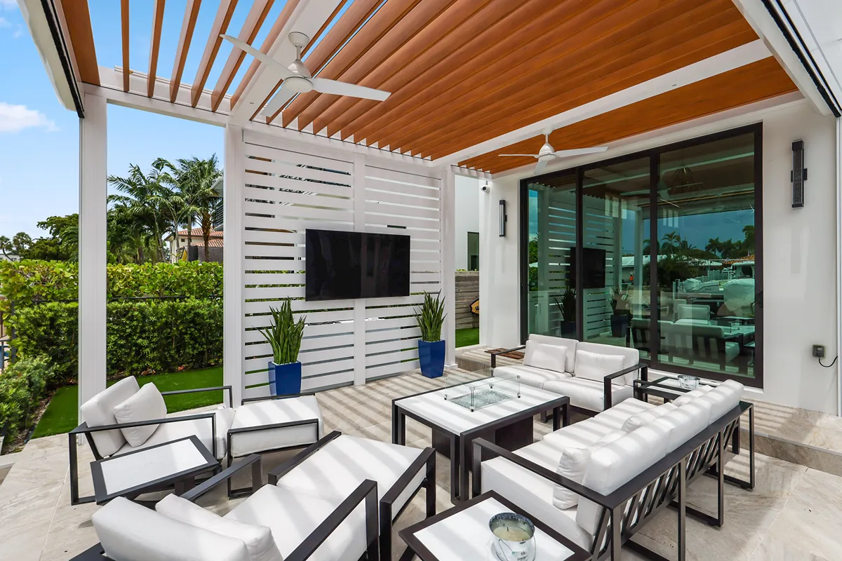 A sleek, modern pergola with a louvered roof system creates a shaded lounge space near a contemporary pool.