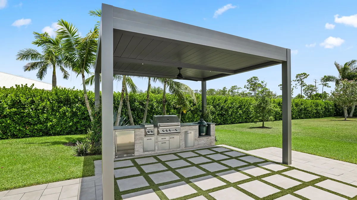 A minimalist, modern pergola shades a luxury outdoor kitchen set in a lush backyard. 