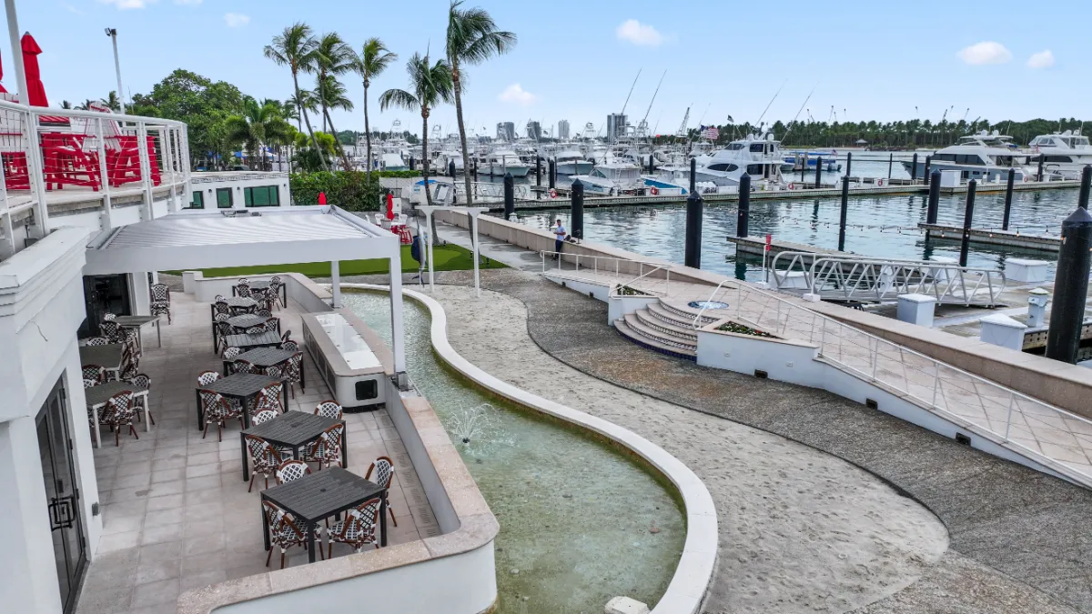 ): Waterfront dining area shaded by a smart pergola, overlooking a marina with yachts and palm trees in the background.