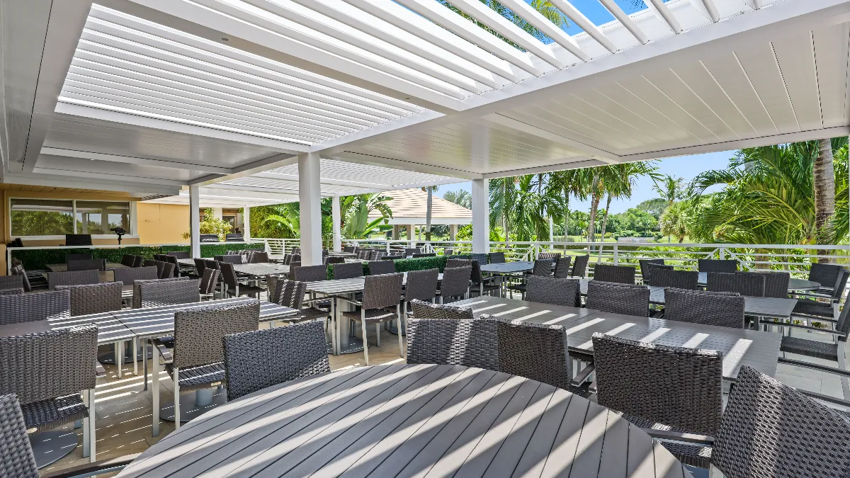 Covered outdoor dining area at Jonathan’s Landing, featuring SYZYGY Global’s motorized pergola and integrated lighting.
