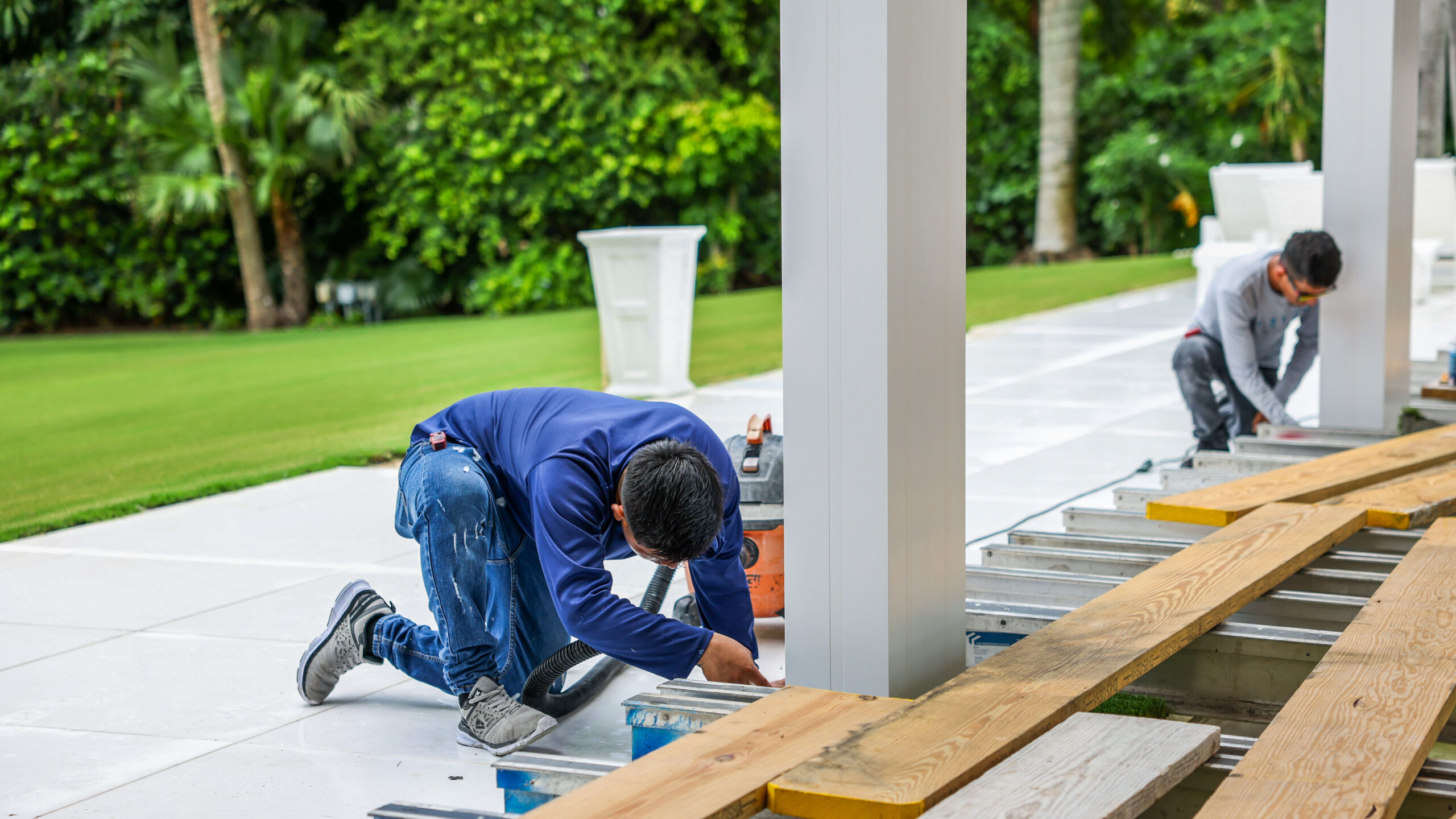 Workers secure pergola posts to concrete footings during a precision installation by SYZYGY Global.