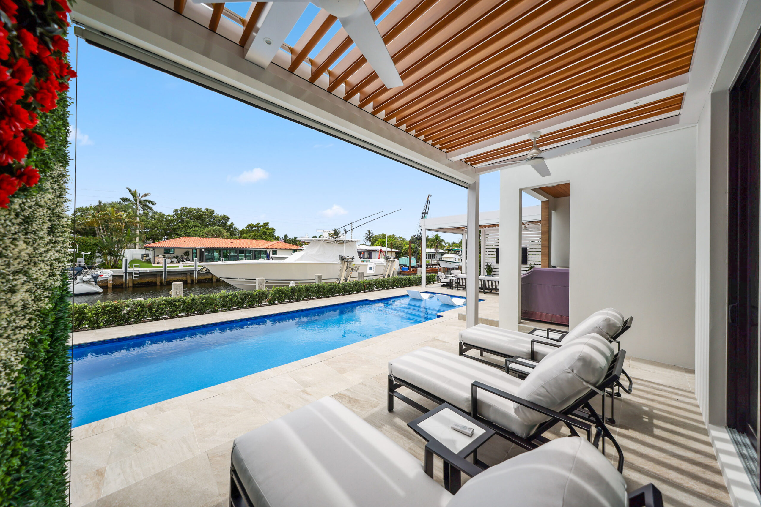 Lean-to pergola with wood-look louvers covering a luxury poolside patio in South Florida.