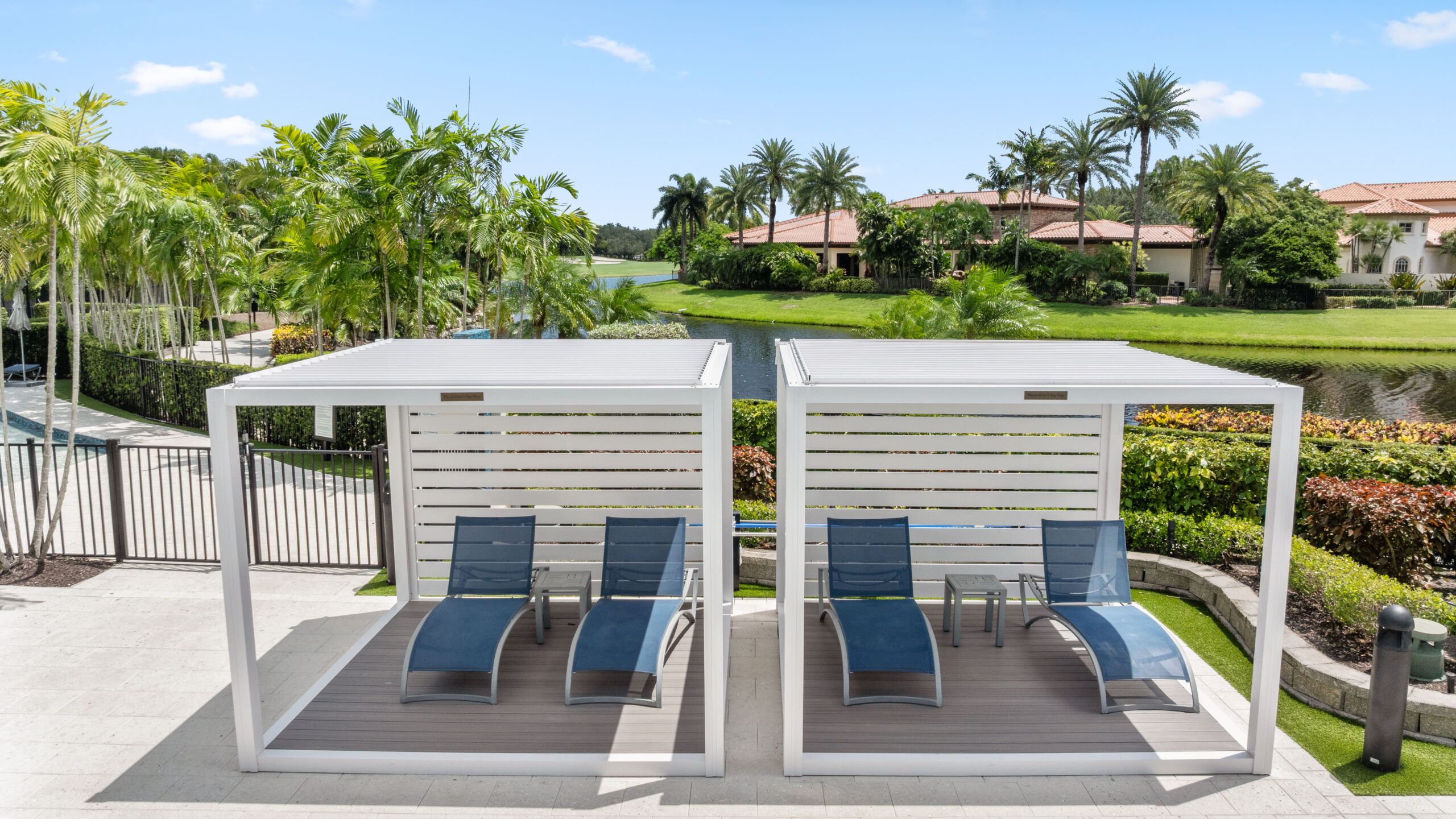 Twin white K-Bana cabanas with lounge chairs overlooking the water at Mizner Country Club in Delray Beach.
