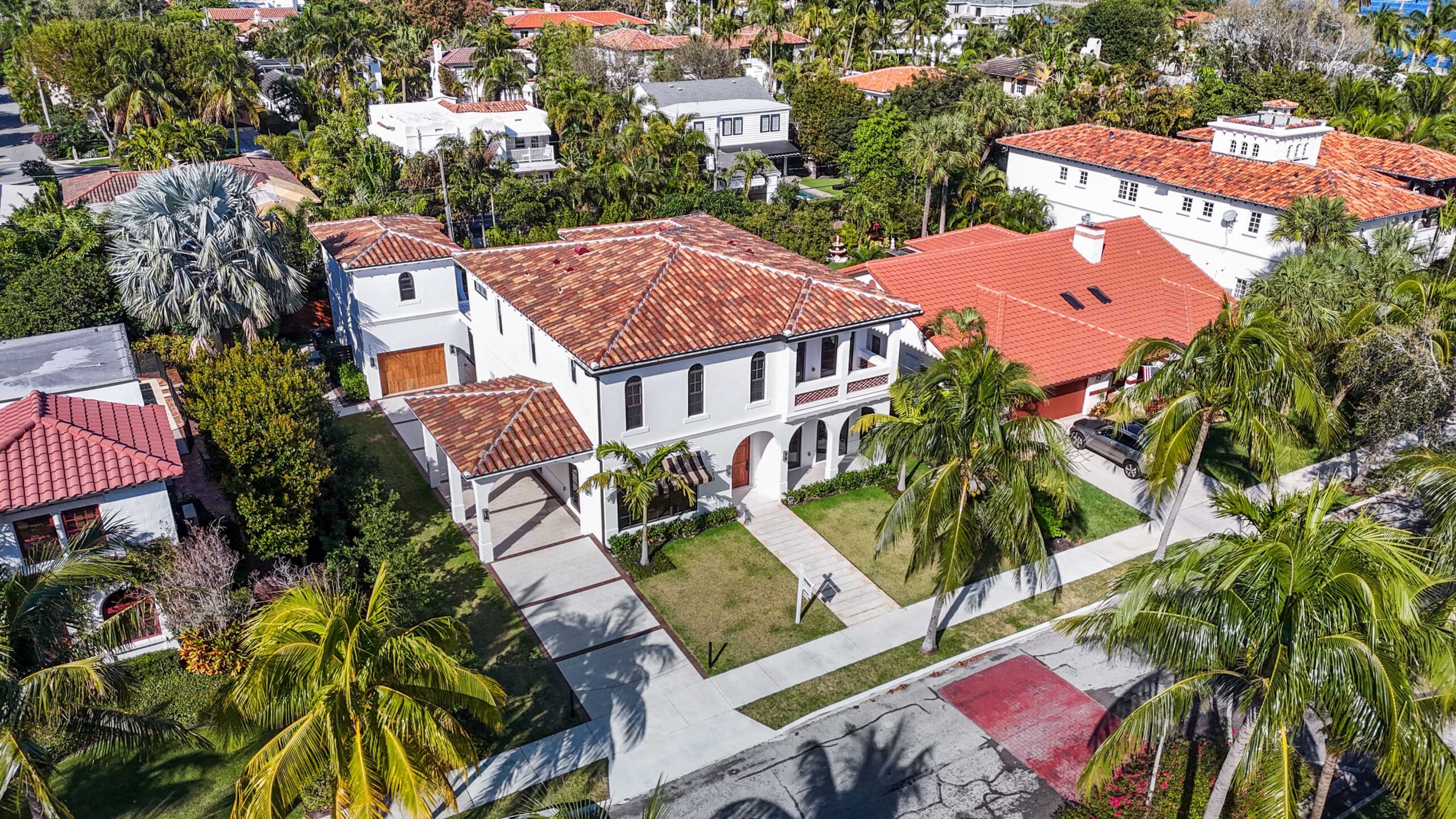 Mediterranean-style home with red tile roof and arched loggia design surrounded by palm trees in South Florida.