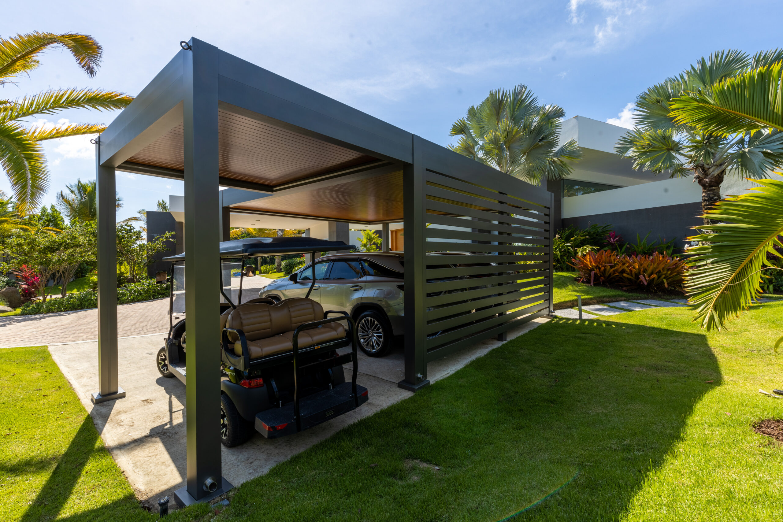 Enclosed carport with wood-grain ceiling and privacy panels sheltering SUVs and golf cart in modern home.