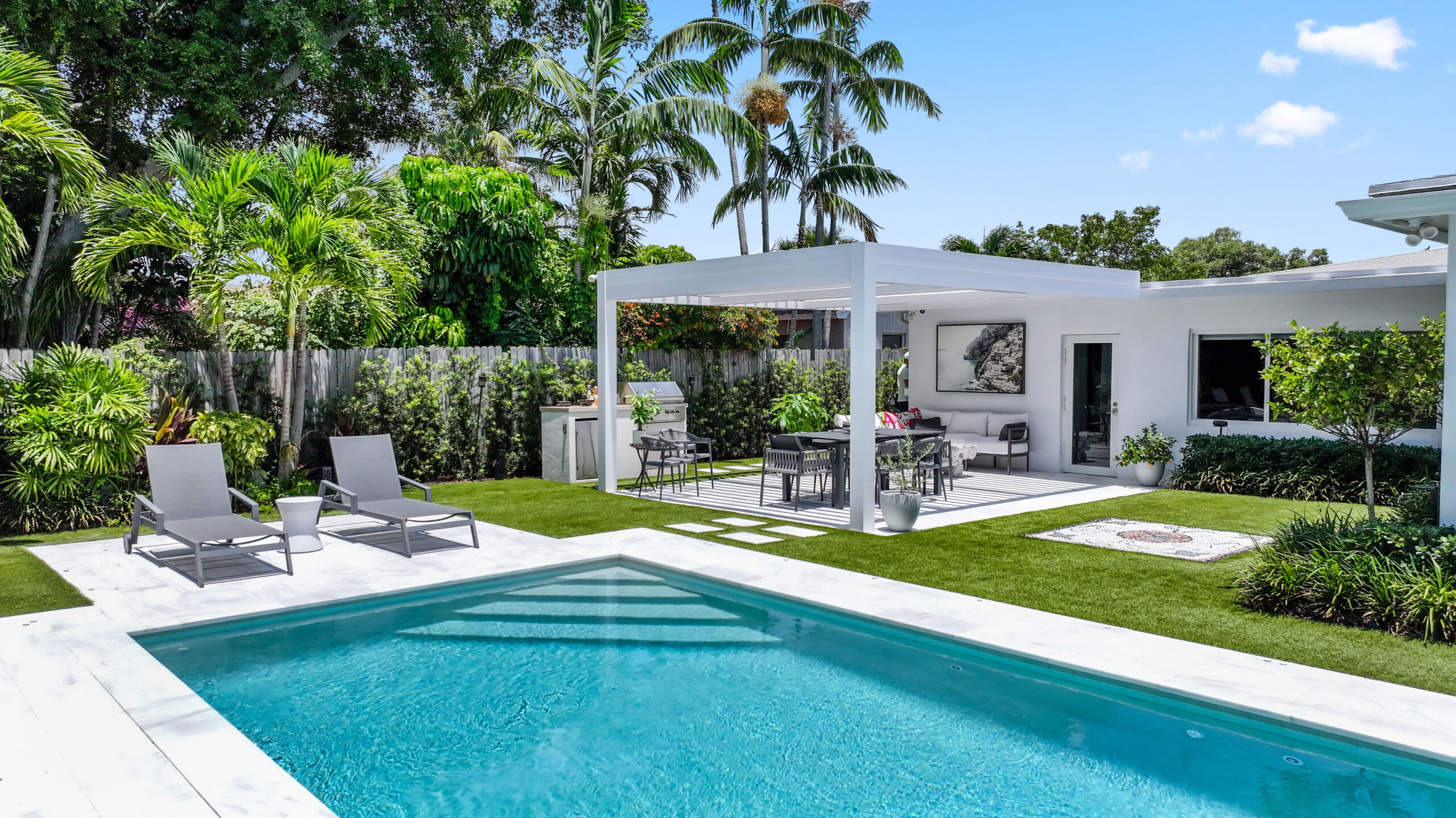 South Florida luxury pergola creating shaded poolside living with outdoor dining and lounge.