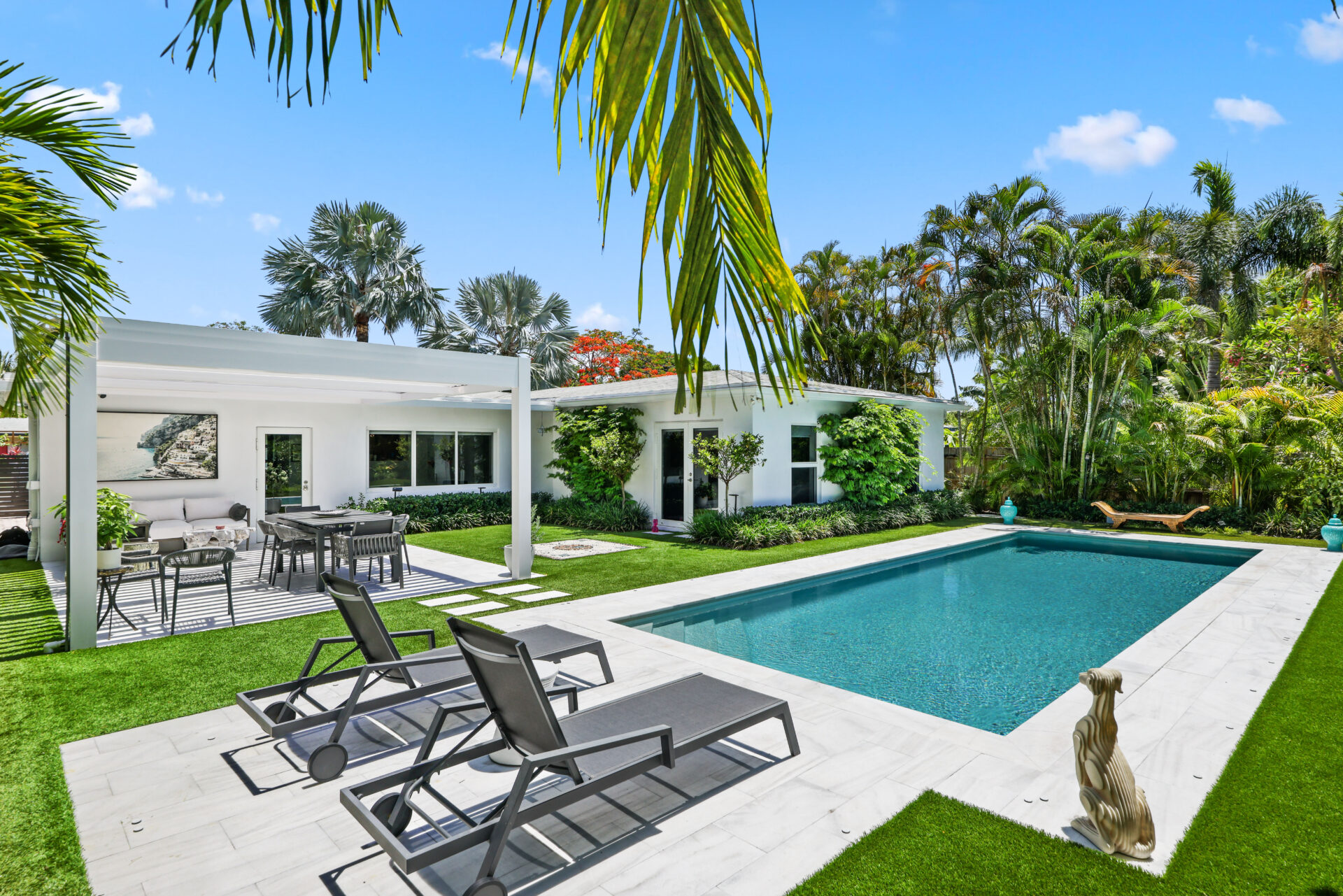 Luxury poolside lounge with covered patio, dining area, and tropical South Florida backyard refresh design.
