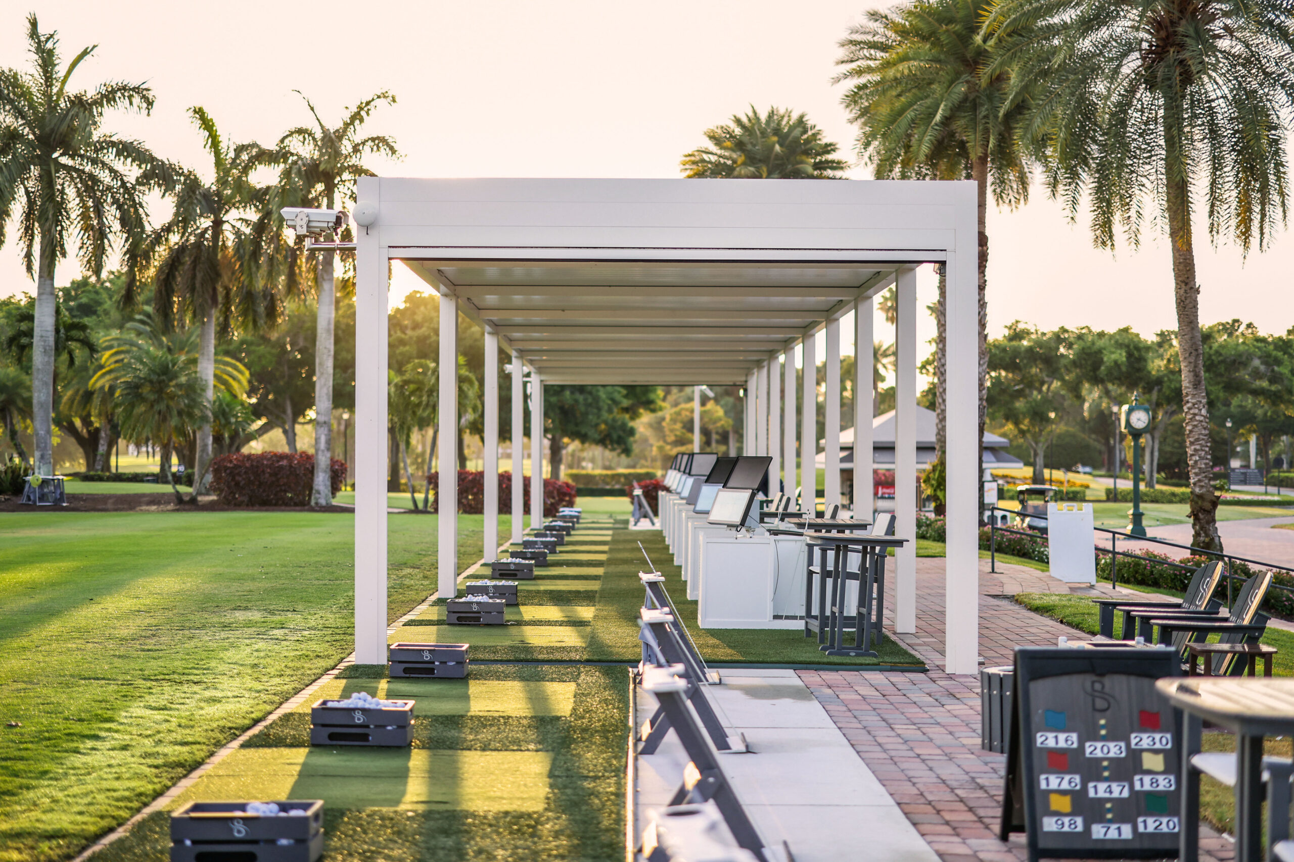 Covered Golf Bays pergola at Broken Sound featuring hitting stations, tech screens, and manicured fairways.
