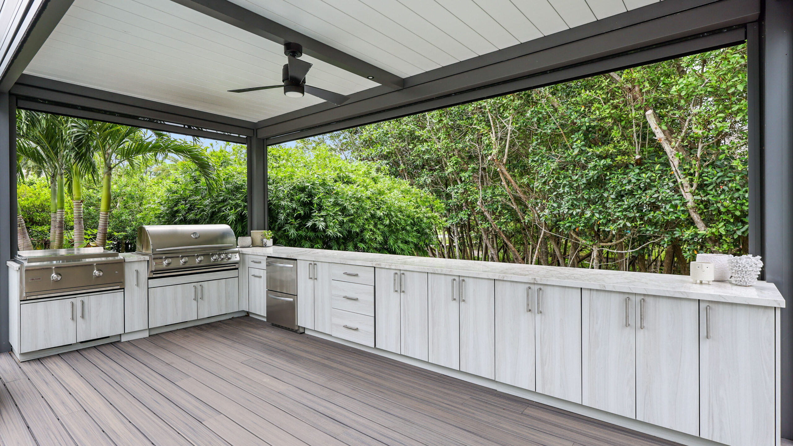 Modern pergola design with integrated outdoor kitchen, aluminum structure, ceiling fan, and luxury backyard setting.