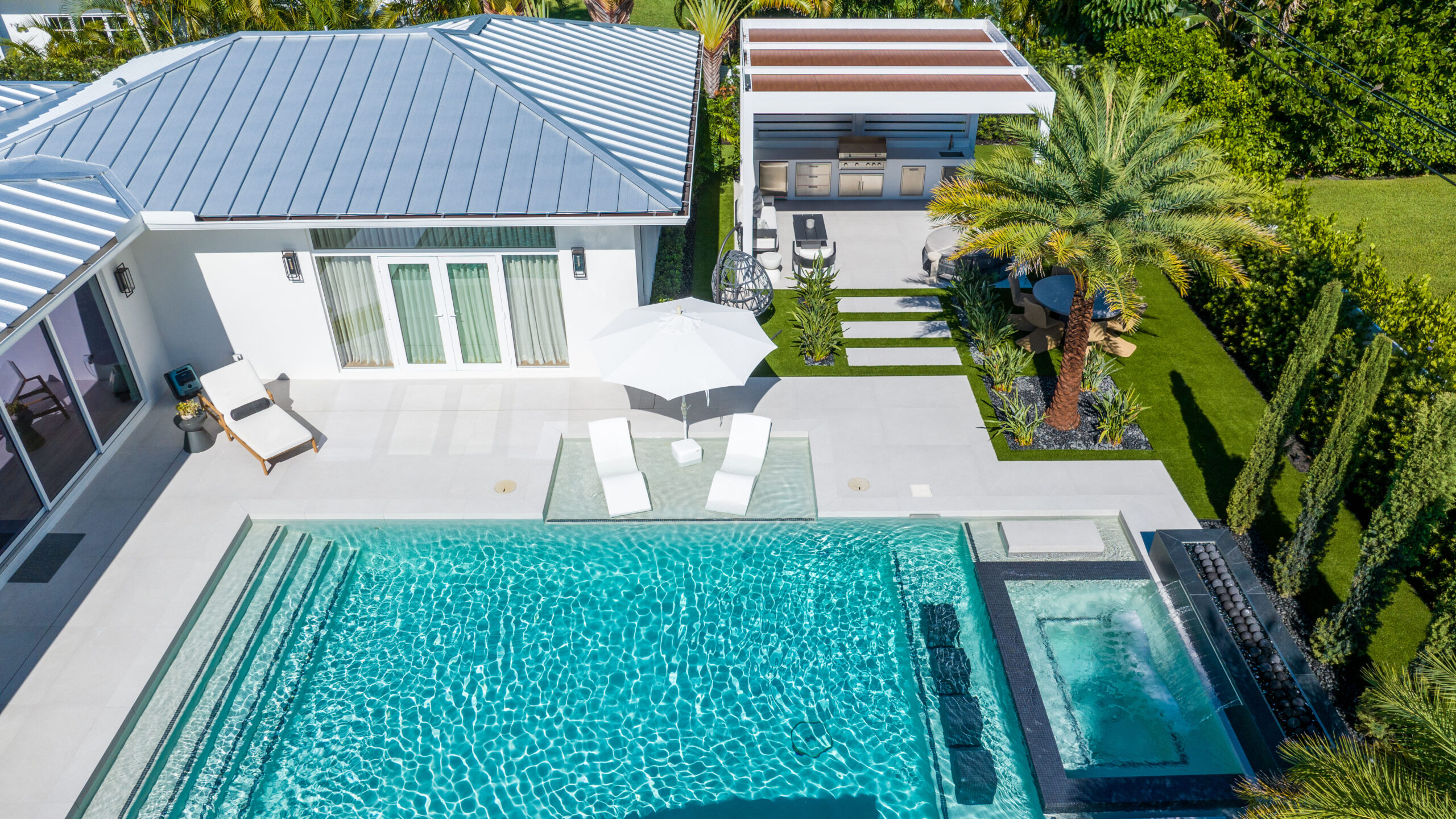 Aerial view of a poolside aluminum pergola and outdoor kitchen, illustrating pergola vs gazebo layout and modern outdoor living design.