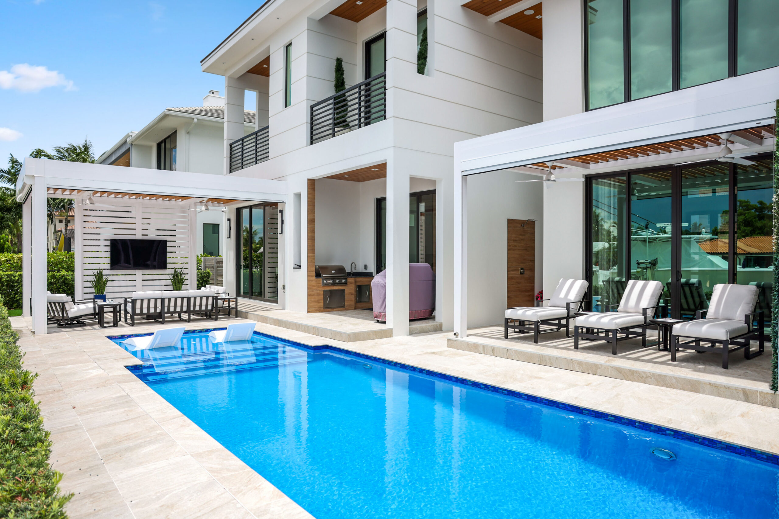 Luxury South Florida poolside patio with shaded pergolas, lounge seating, and modern outdoor living design.