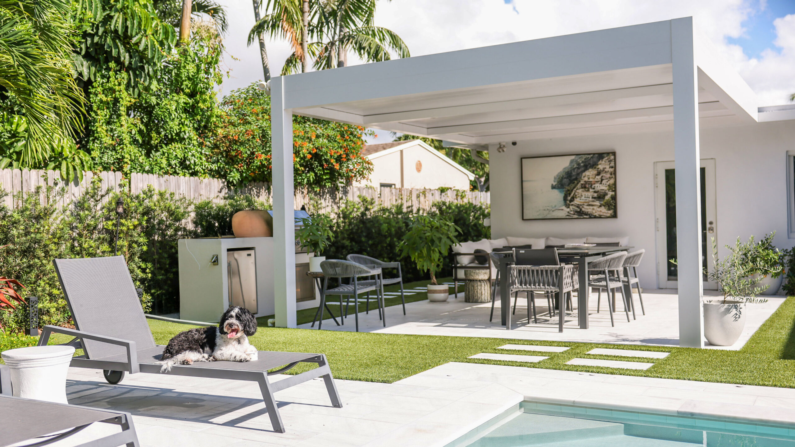 Hurricane-rated aluminum pergola shading a modern Florida backyard lounge and dining area beside a pool.