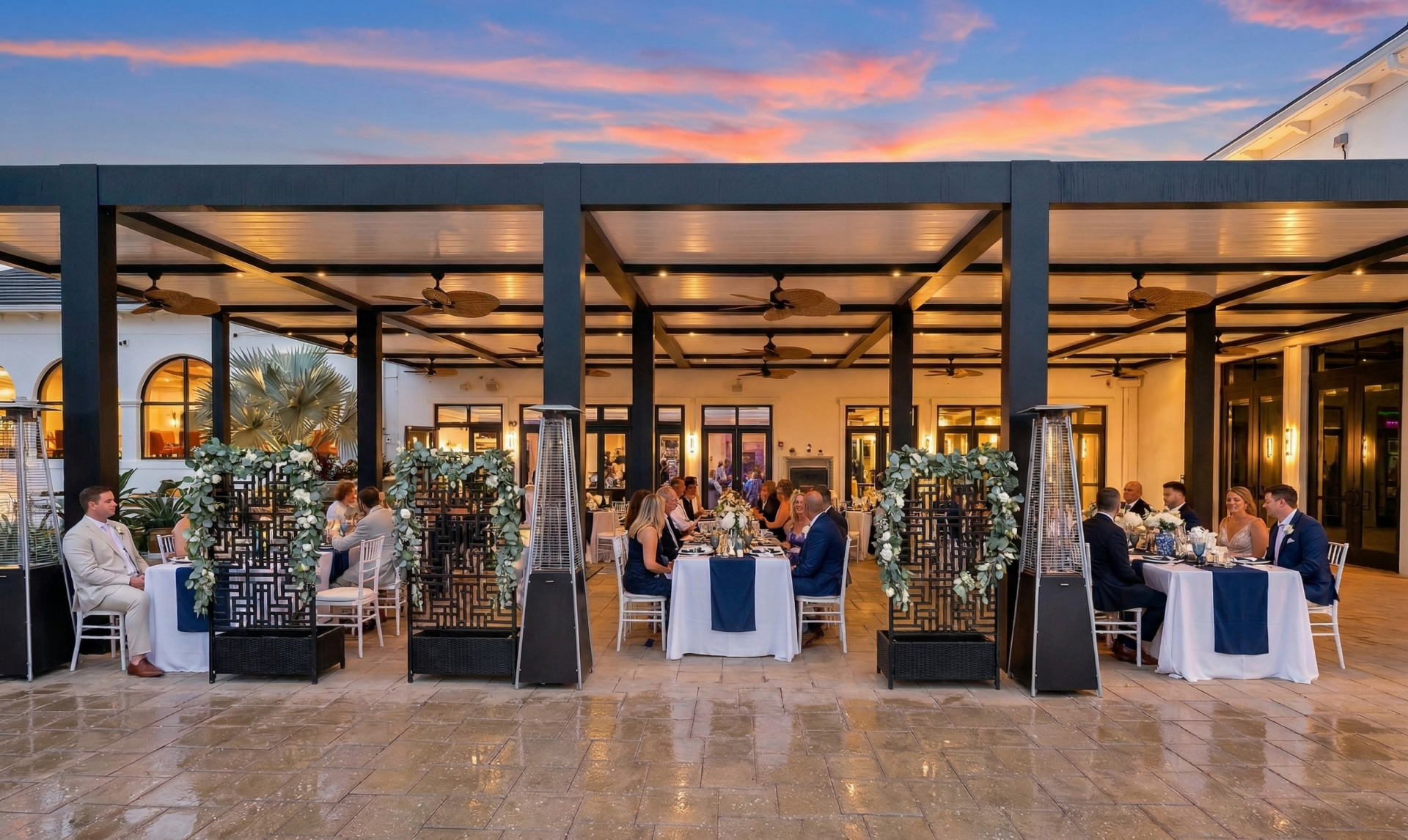 Covered outdoor wedding reception under a luxury pergola with rain protection at a South Florida venue.