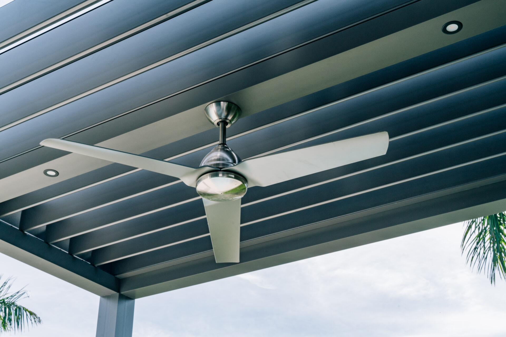 Motorized louvered pergola ceiling with integrated fan and adjustable aluminum louvers.