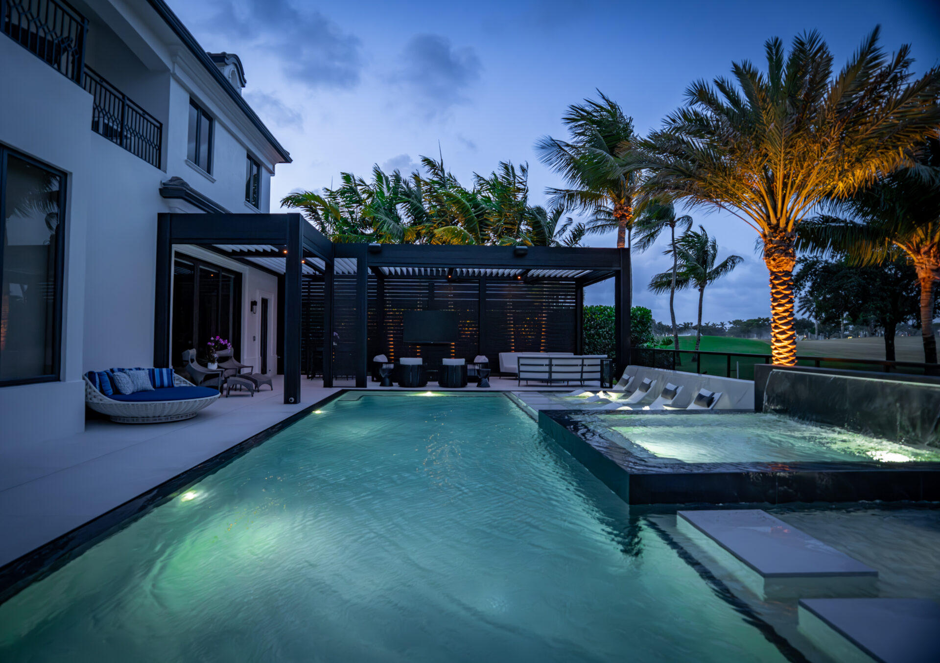 Louvered pergola with integrated lighting beside a pool and spa at dusk, South Florida luxury outdoor living.