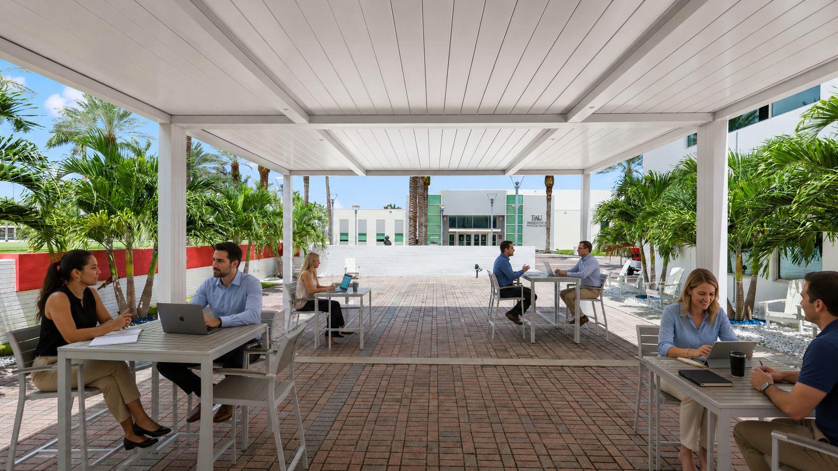 Professionals working outdoors under white commercial pergola structure, open-air courtyard with brick pavers and palm trees.
